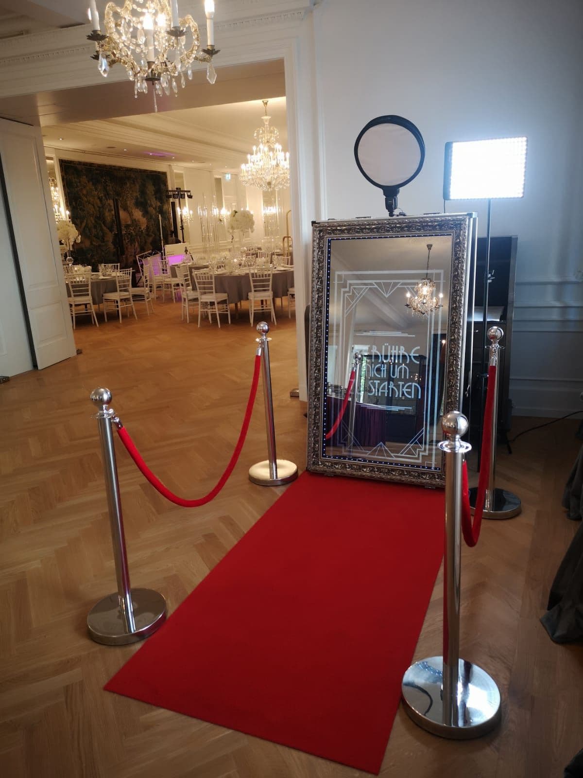 Aufgebauter Fotospiegel mit rotem Teppich, Absperrung und Blitzlicht in einem Festsaal